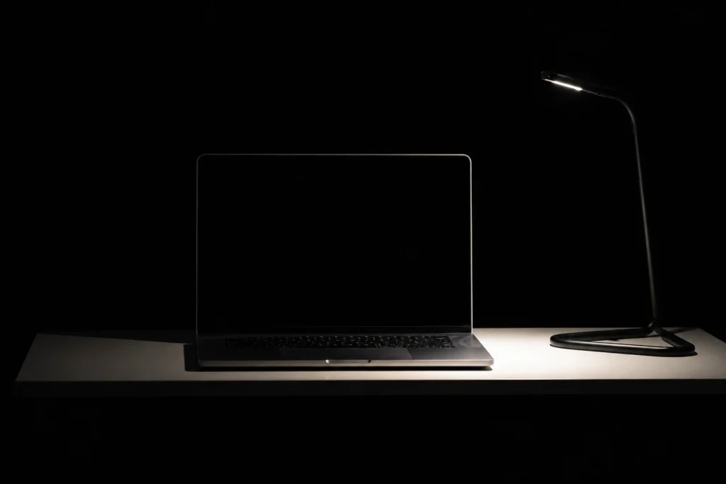 Minimal dark workspace with laptop and desk lamp representing focused SEO strategy and digital work